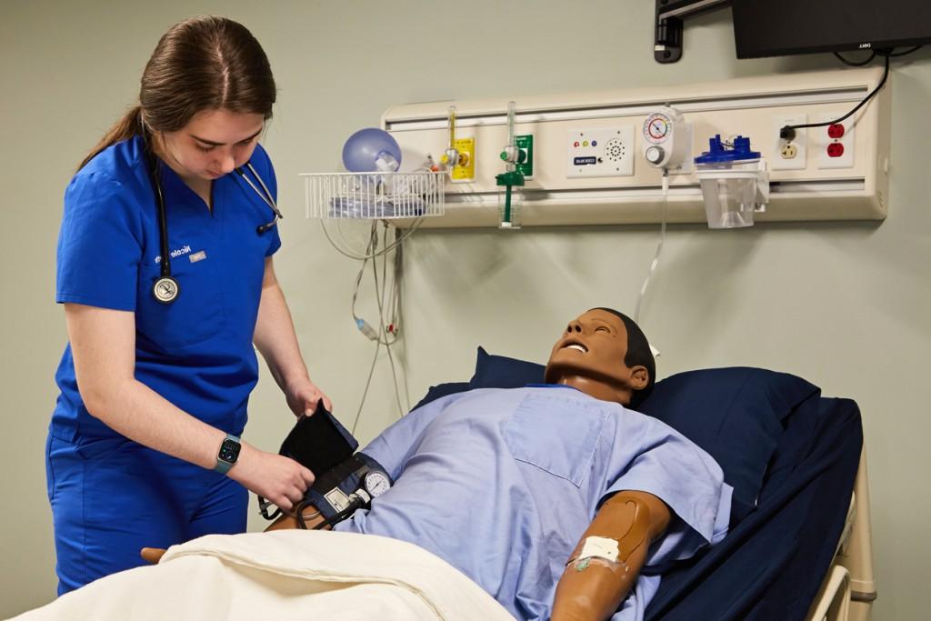 一位医师助理学生在病人模拟器上练习测量血压