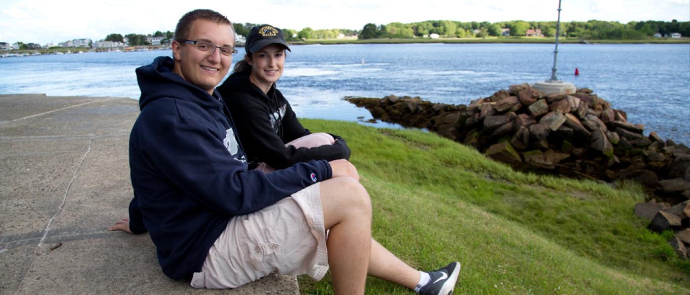 Two students sitting together on Jordan Point in front of the water