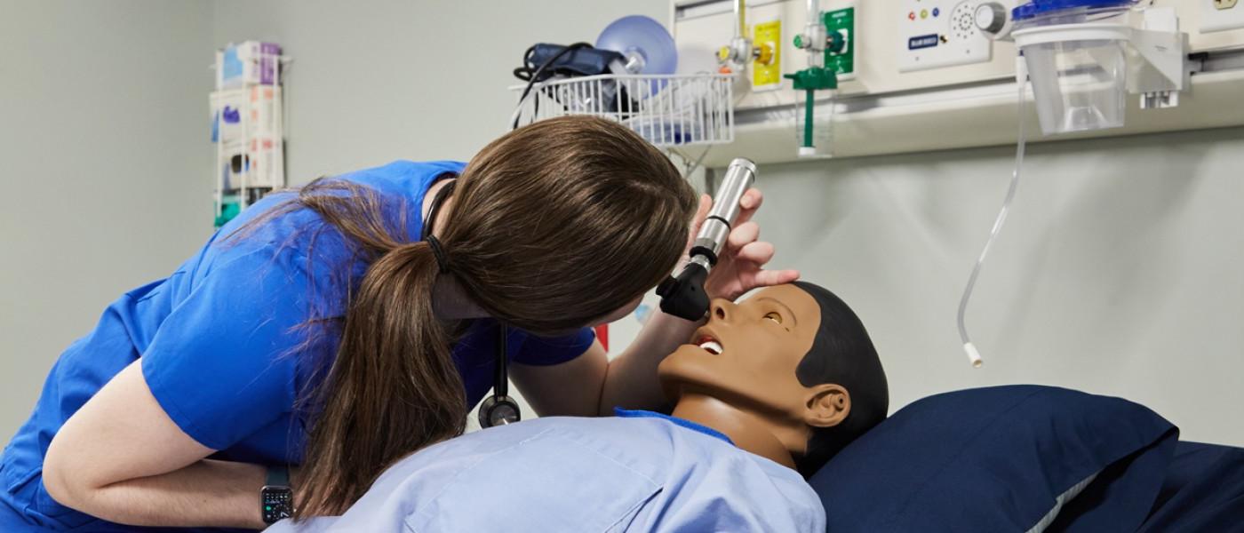一名医师助理学生在病人模拟器上使用耳镜