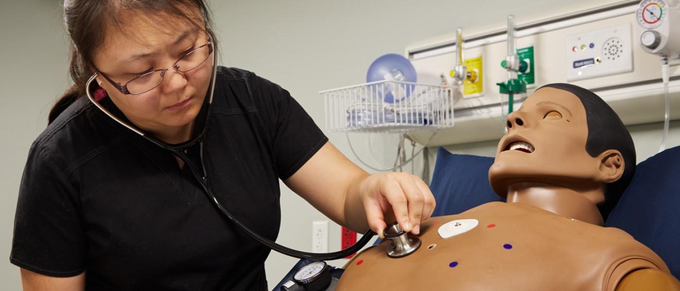 一位医师助理学生用听诊器听病人的心跳