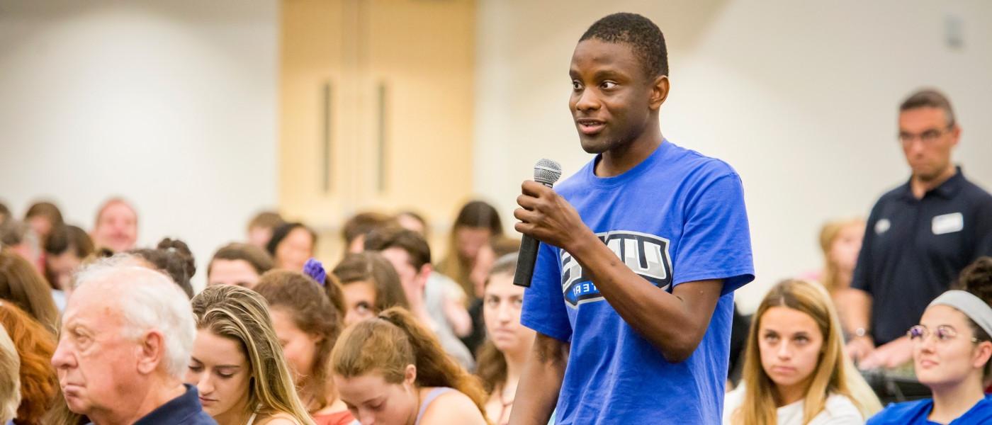 一名身穿蓝色联合国大学t恤的学生向参加总统论坛活动的人群提问